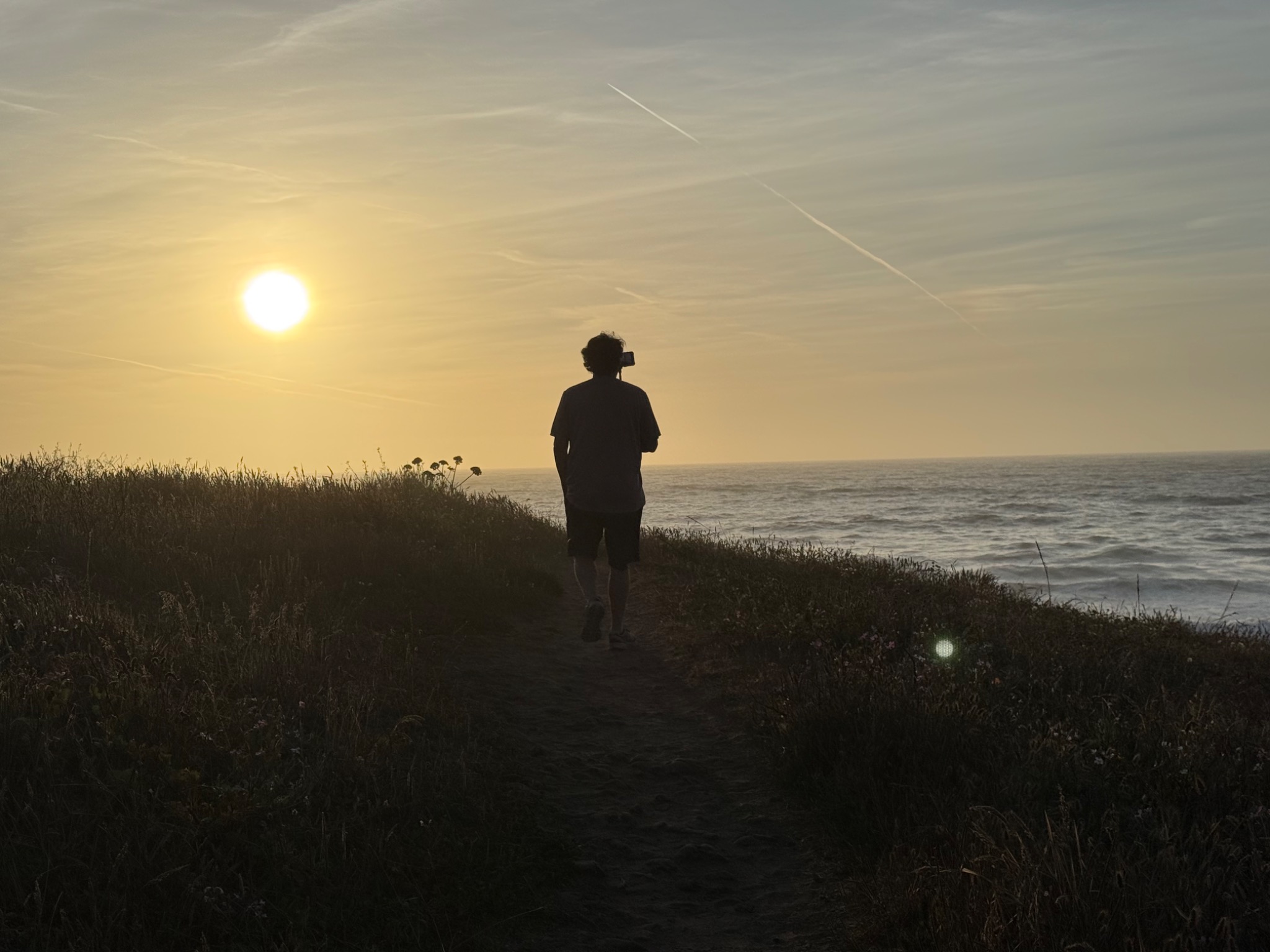 Person walking a coastal trail at sunset